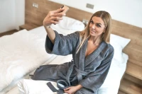 Dámský froté župan střihu kimono tmavě šedý - žena fotící se na posteli
